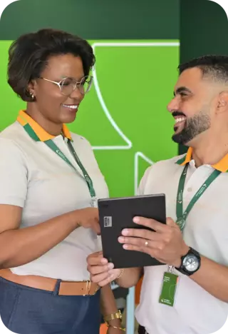 Dois colaboradores de uma das lojas Localiza Seminovos conversando e analisando informações em um tablet, ambos vestindo uniformes com a logo da empresa ao fundo